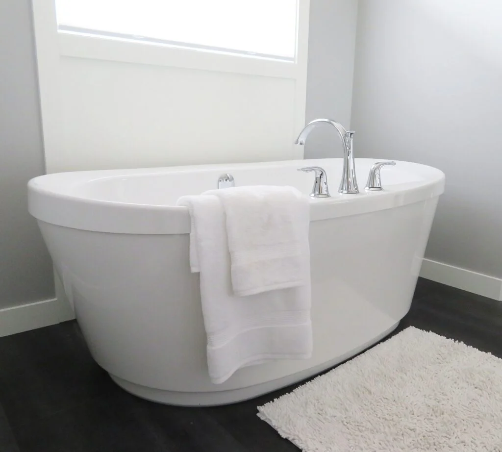 Freistehende Badewanne mit Handtüchern und Badteppich