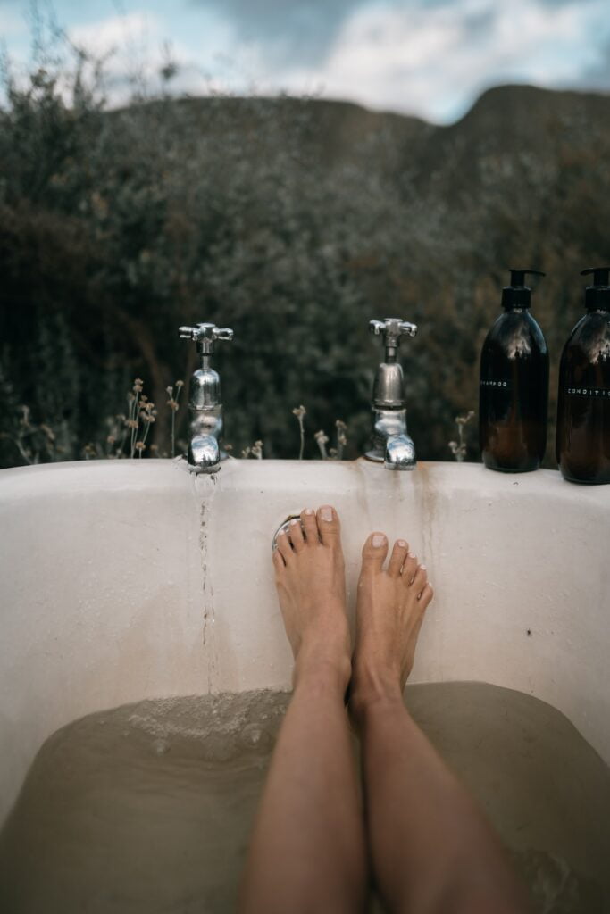 Füße in Badewanne mit Wasserhähnen